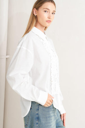 A solid woven top with a collar, button-down front, long sleeves, and front ruffle detail.