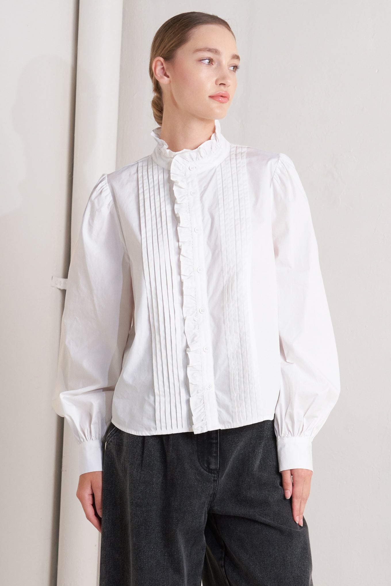 A solid woven top featuring ruffled high neckline, long sleeve and front button down closure