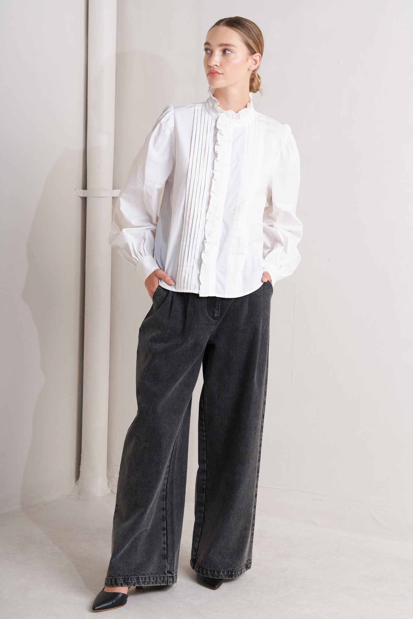 A solid woven top featuring ruffled high neckline, long sleeve and front button down closure