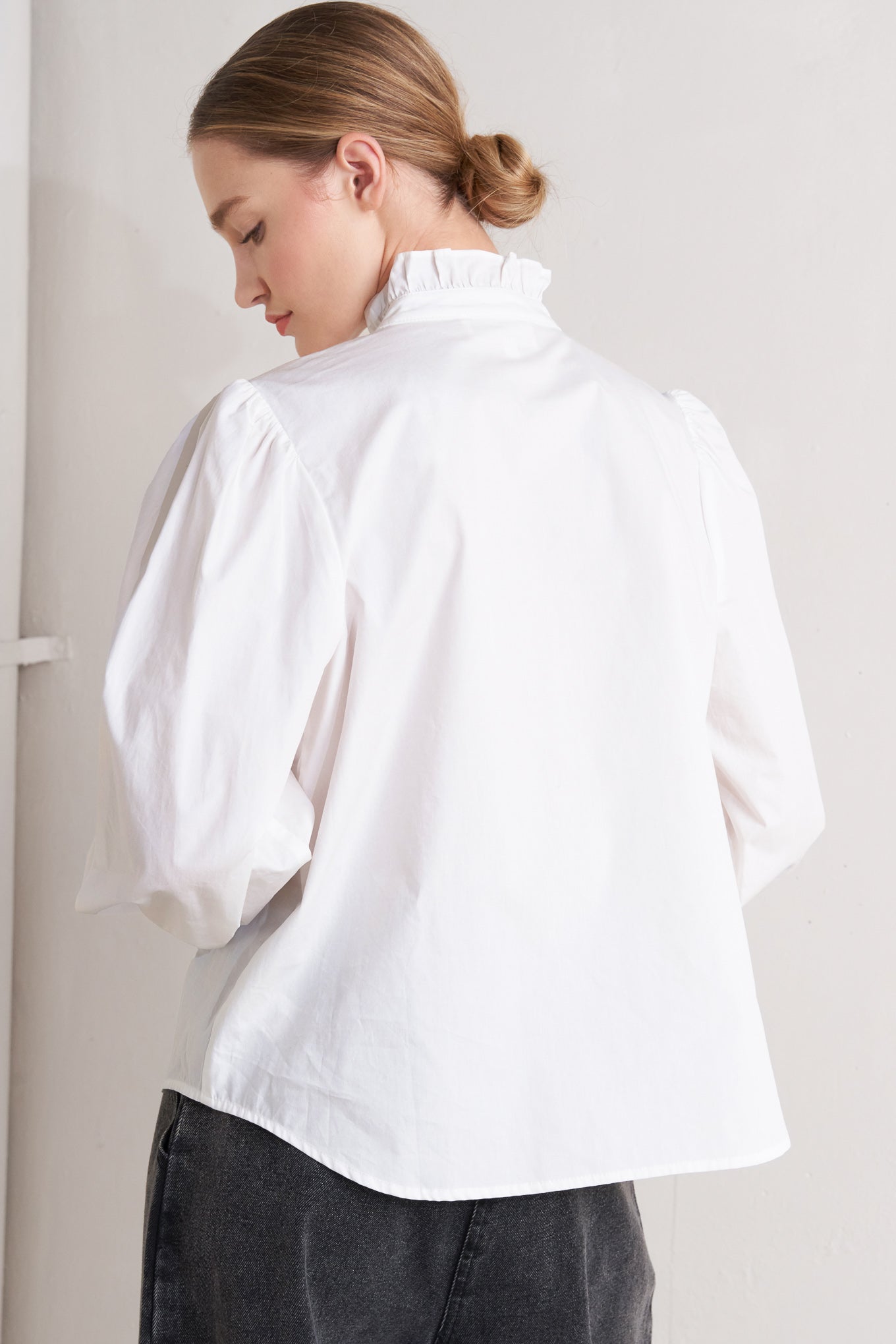 A solid woven top featuring ruffled high neckline, long sleeve and front button down closure