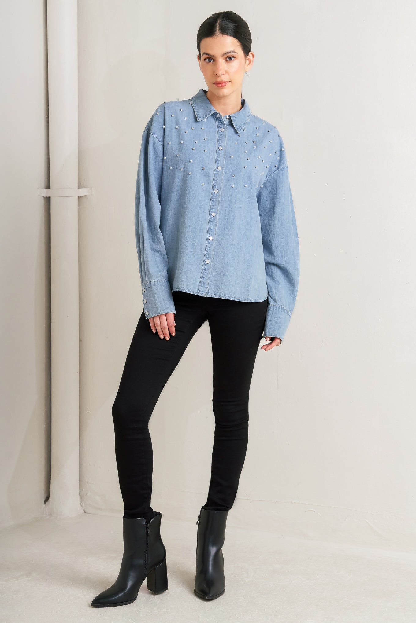 Woman wearing a light blue denim shirt with decorative elements on a plain background - FLYING TOMATO