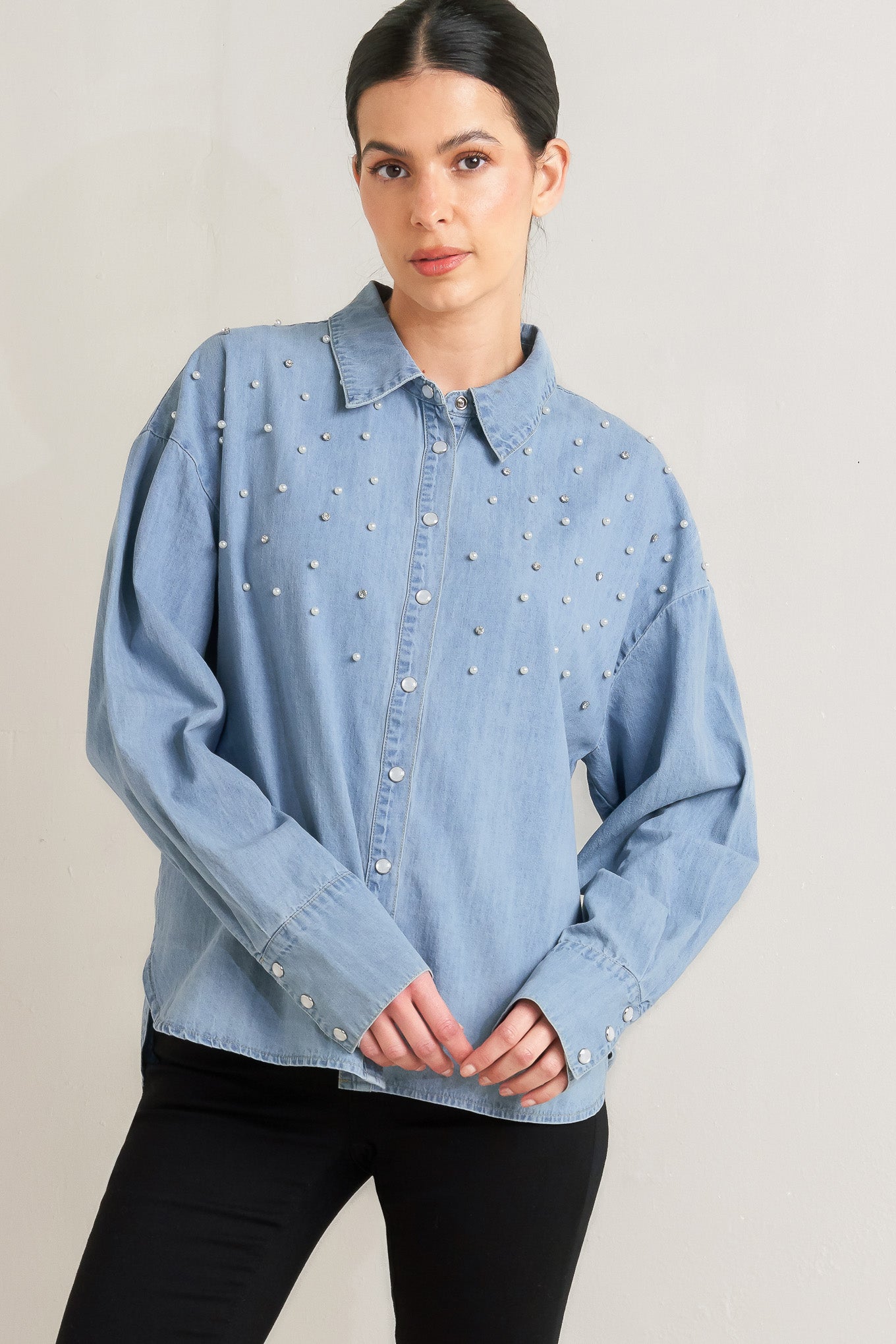 Woman wearing a light blue denim shirt with decorative elements on a plain background - FLYING TOMATO