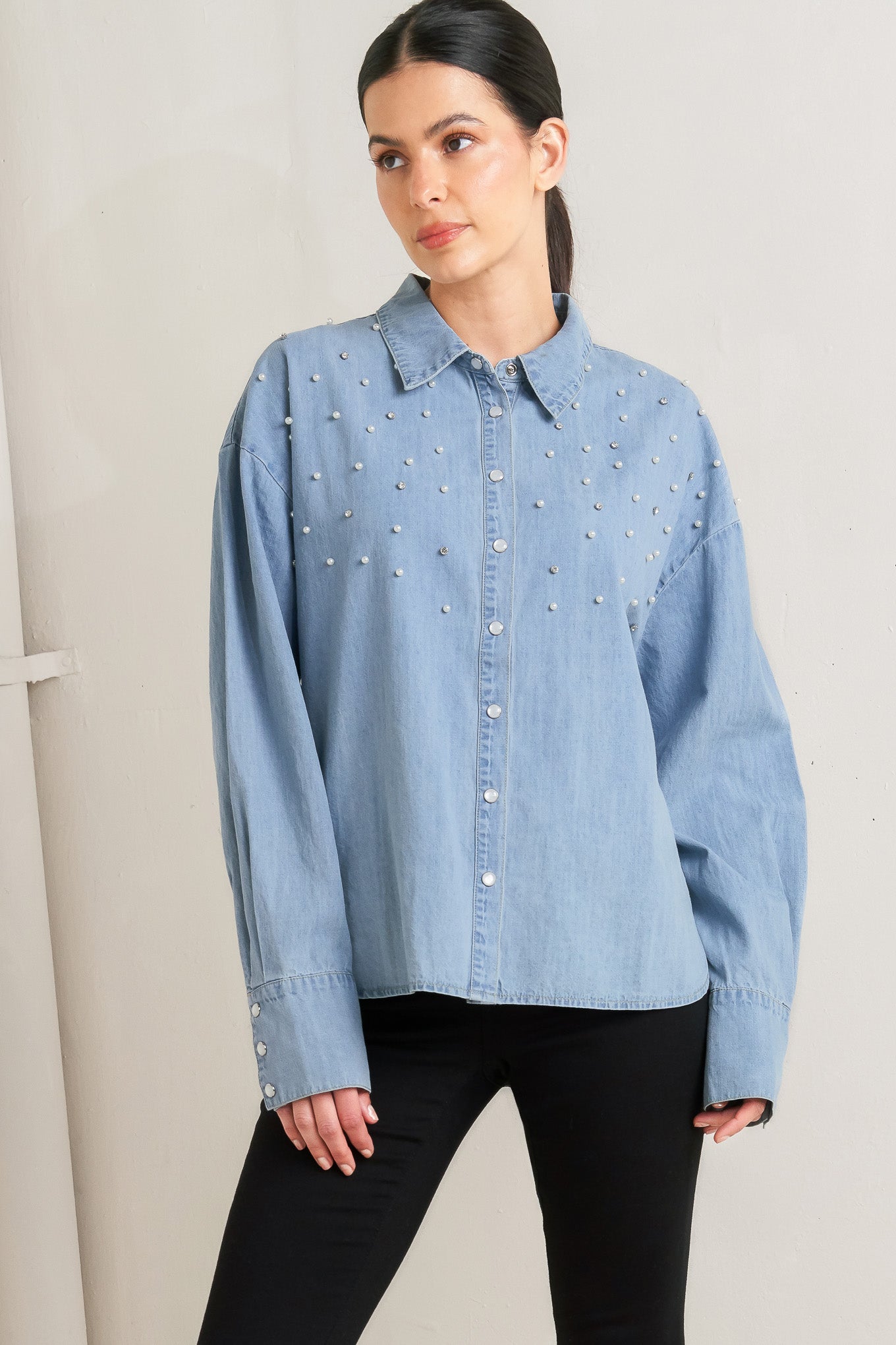 Woman wearing a light blue denim shirt with decorative elements on a plain background - FLYING TOMATO