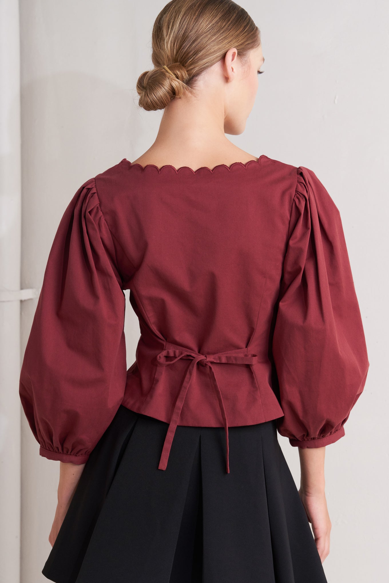 A solid woven top featuring scalloped square neckline, 3/4 sleeve and front button down closure