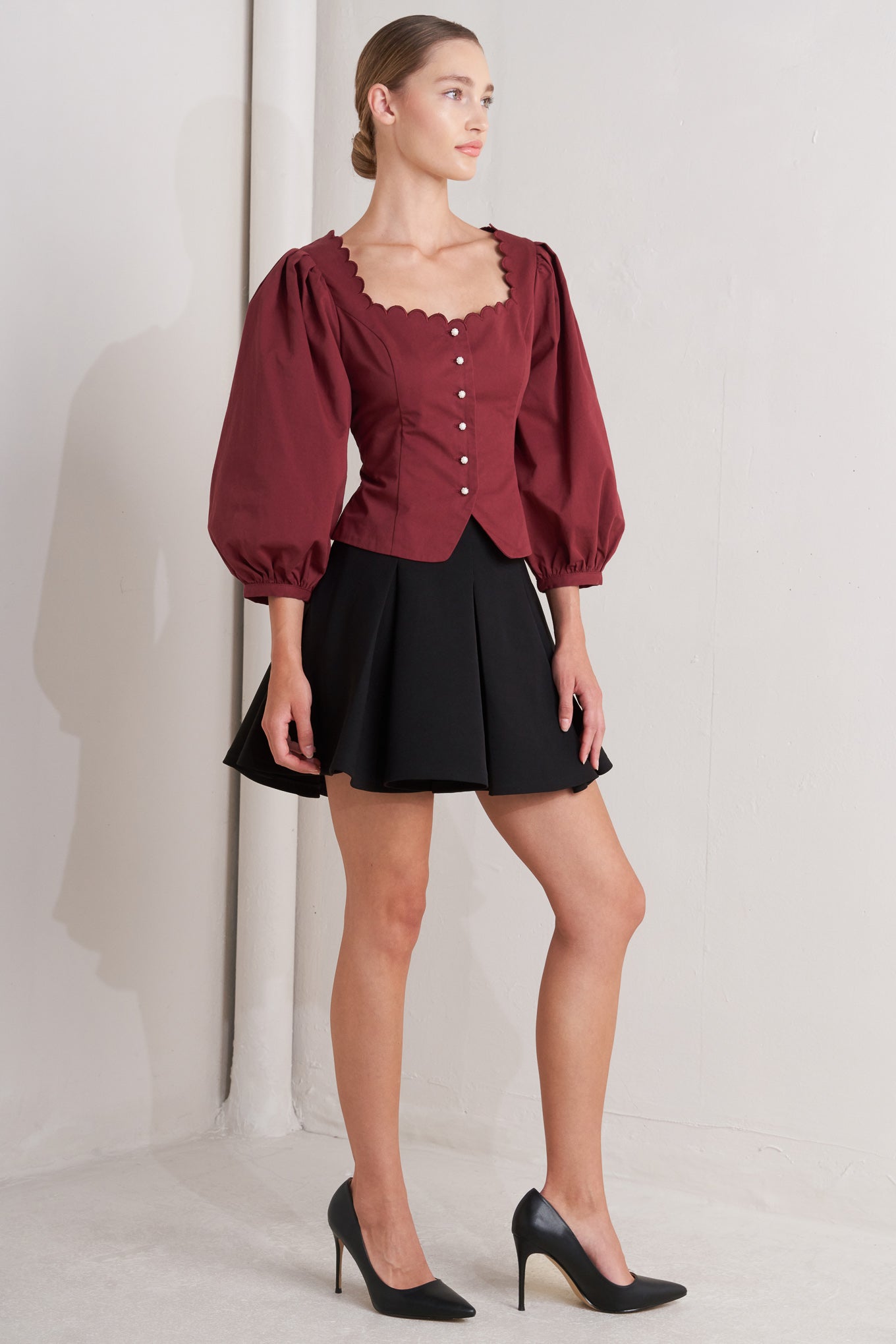 A solid woven top featuring scalloped square neckline, 3/4 sleeve and front button down closure