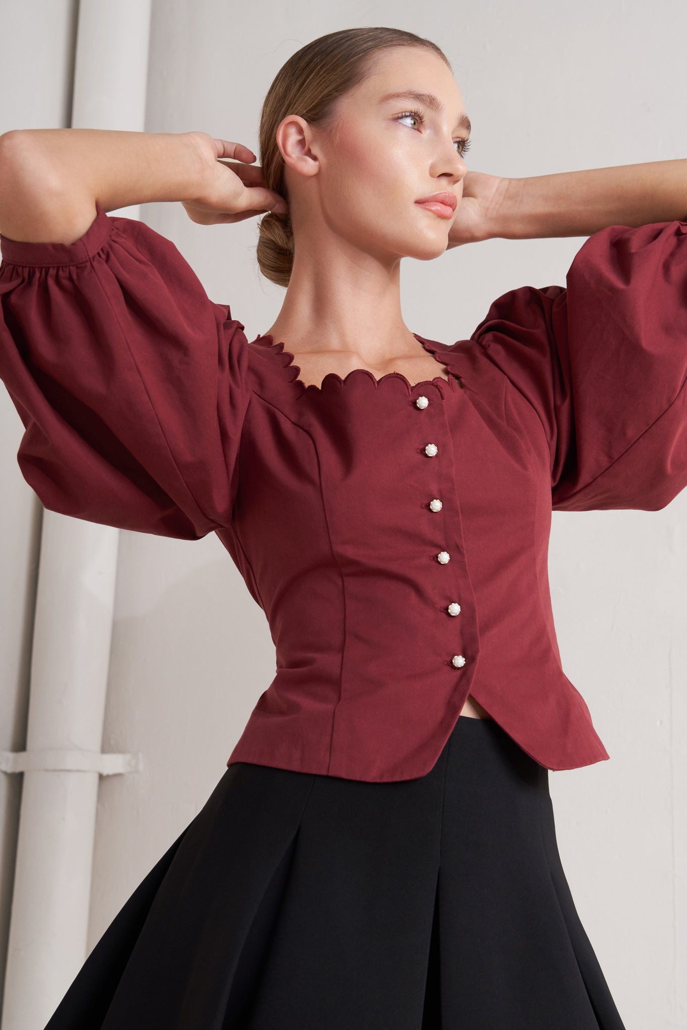A solid woven top featuring scalloped square neckline, 3/4 sleeve and front button down closure
