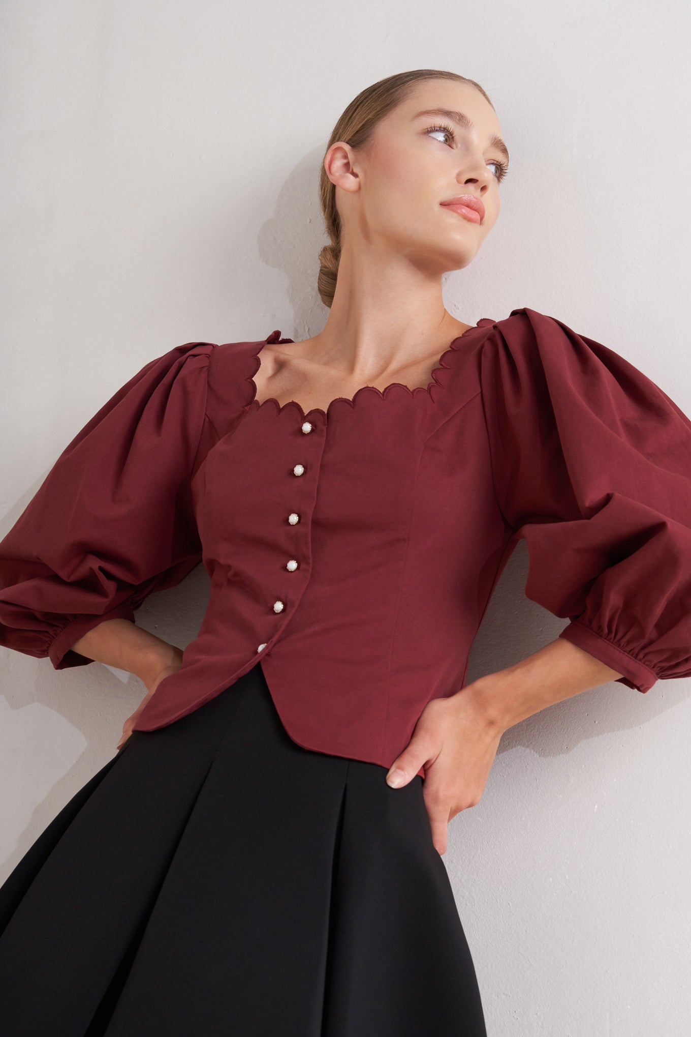 A solid woven top featuring scalloped square neckline, 3/4 sleeve and front button down closure