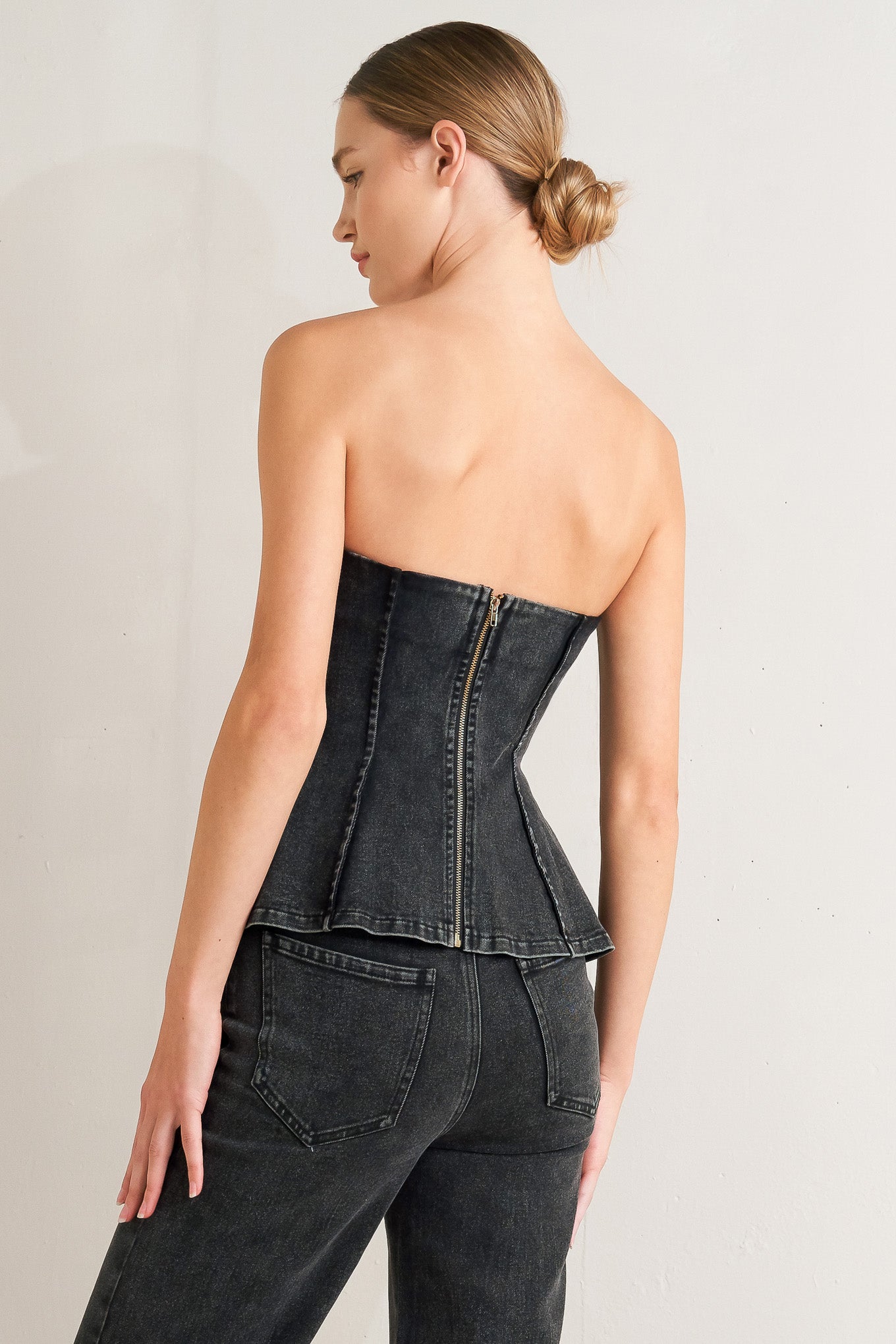A washed denim top featuring strapless neckline and back zipper closure