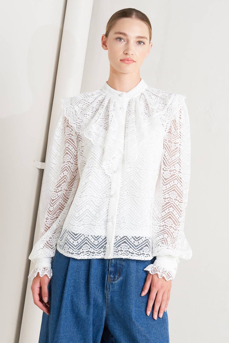A woven lace top featuring high neckline, ruffles, long sleeve with cuff, button down closure and cami