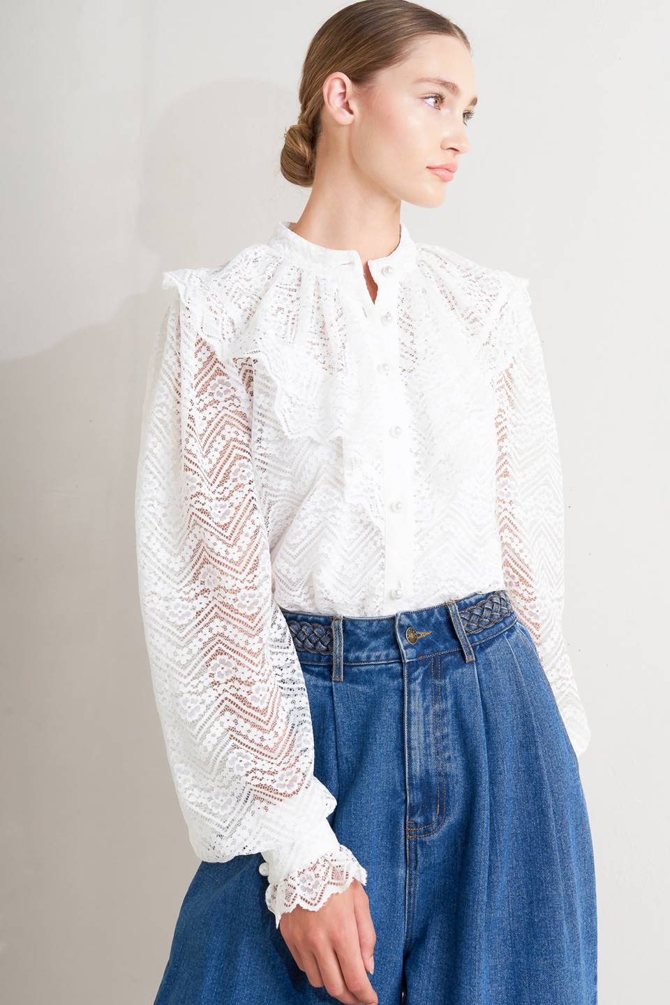 A woven lace top featuring high neckline, ruffles, long sleeve with cuff, button down closure and cami