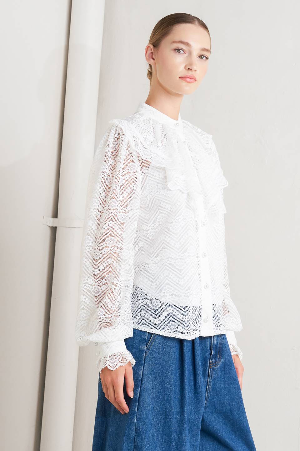 A woven lace top featuring high neckline, ruffles, long sleeve with cuff, button down closure and cami