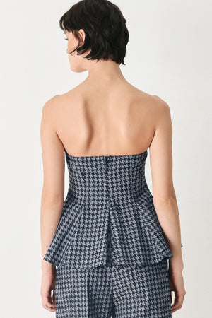 Woman wearing a strapless houndstooth patterned tube top with peplum and back zipper closure | FREEMARKET