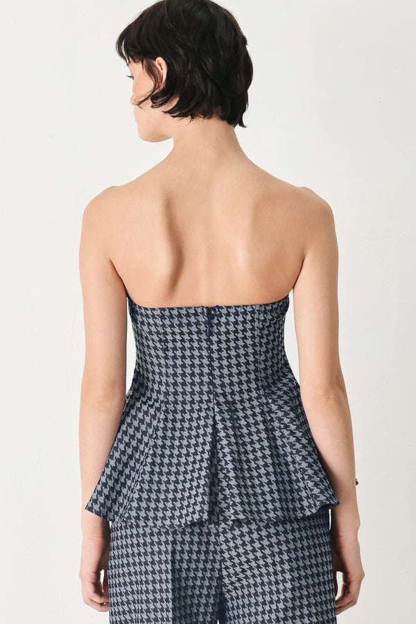 Woman wearing a strapless houndstooth patterned tube top with peplum and back zipper closure | FREEMARKET