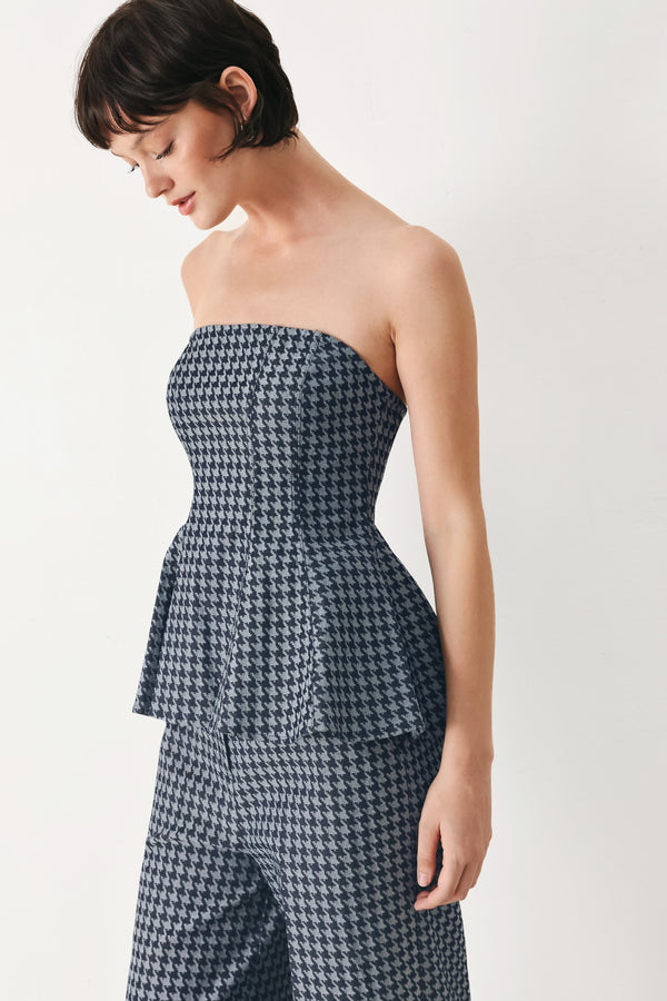 Woman wearing a strapless houndstooth patterned tube top with peplum and back zipper closure | FREEMARKET