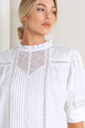 A solid woven top featuring ruffled high neck, pintuck and lace inset, short puff sleeve and back neck button closure

Details:

Self: 100% Cotton Exclusive of Decoration

Size & Fit

- Model is 5`8" And Wearing Size Small
- Measurements Taken From Size Small
- Approx. Length: 23"