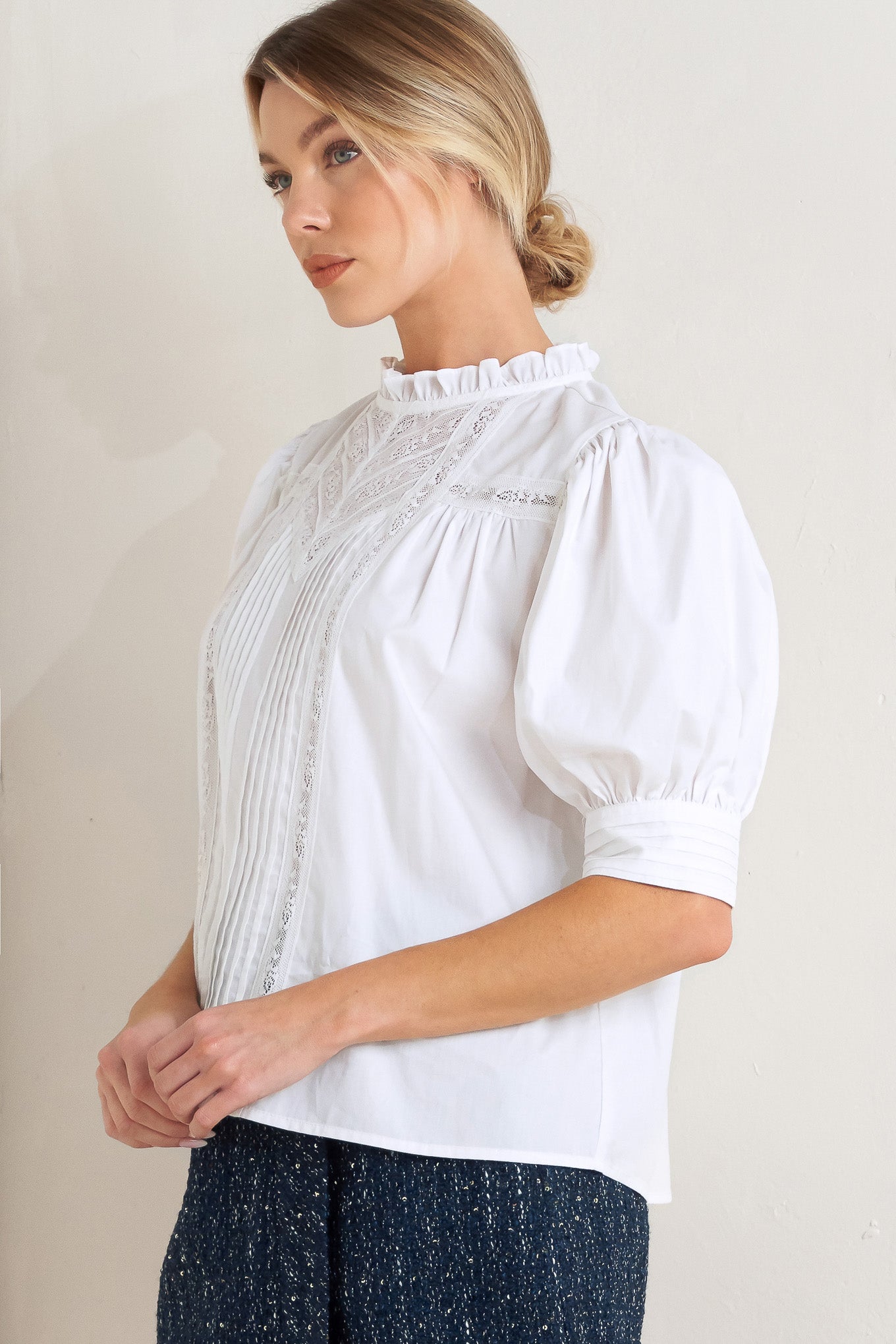 A solid woven top featuring ruffled high neck, pintuck and lace inset, short puff sleeve and back neck button closure

Details:

Self: 100% Cotton Exclusive of Decoration

Size & Fit

- Model is 5`8" And Wearing Size Small
- Measurements Taken From Size Small
- Approx. Length: 23"