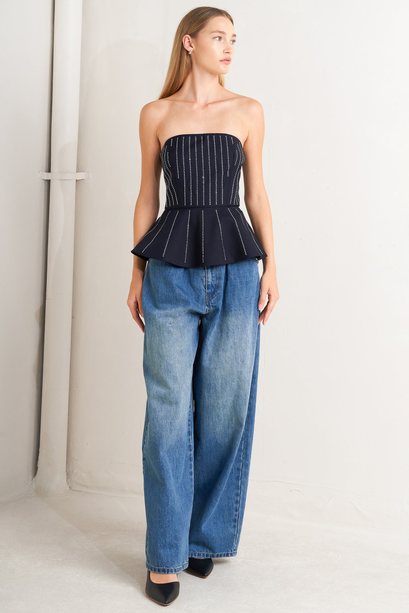 A solid woven top with embellishment, strapless neckline, peplum and back zipper closure