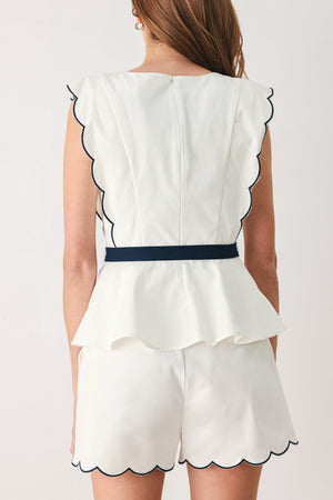 A close-up side view of a woman wearing a white sleeveless top with scalloped edges and a navy blue waist tie | FREEMARKET
