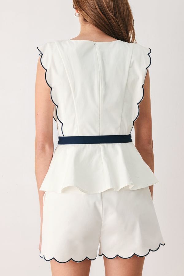 A close-up side view of a woman wearing a white sleeveless top with scalloped edges and a navy blue waist tie | FREEMARKET