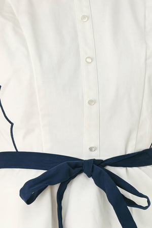 A close-up side view of a woman wearing a white sleeveless top with scalloped edges and a navy blue waist tie | FREEMARKET