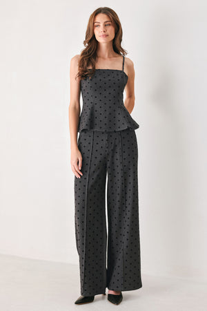 Woman wearing a spaghetti strap charcoal grey top with black polka dots and a peplum waist | FREEMARKET