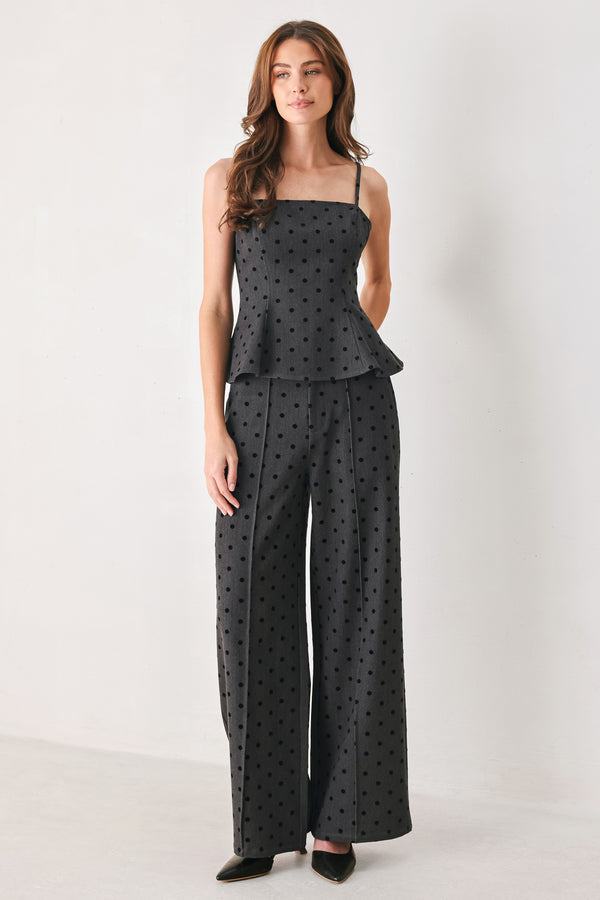 Woman wearing a spaghetti strap charcoal grey top with black polka dots and a peplum waist | FREEMARKET