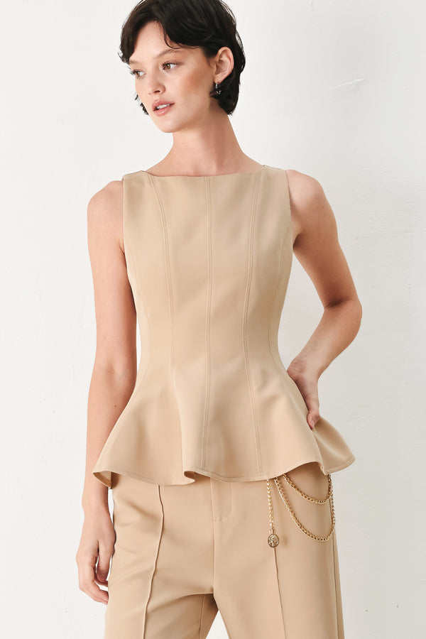Woman wearing a camel sleeveless top with boat neckline, peplum and back zipper closure | FREEMARKET