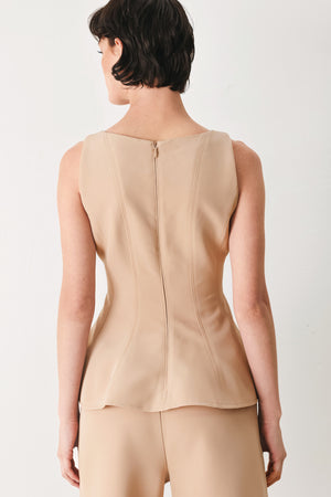 Woman wearing a camel sleeveless top with boat neckline, peplum and back zipper closure | FREEMARKET