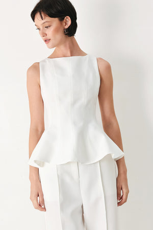 Woman wearing a white sleeveless top with boat neckline, peplum and back zipper closure | FREEMARKET