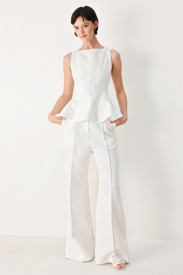 Woman wearing a white sleeveless top with boat neckline, peplum and back zipper closure | FREEMARKET