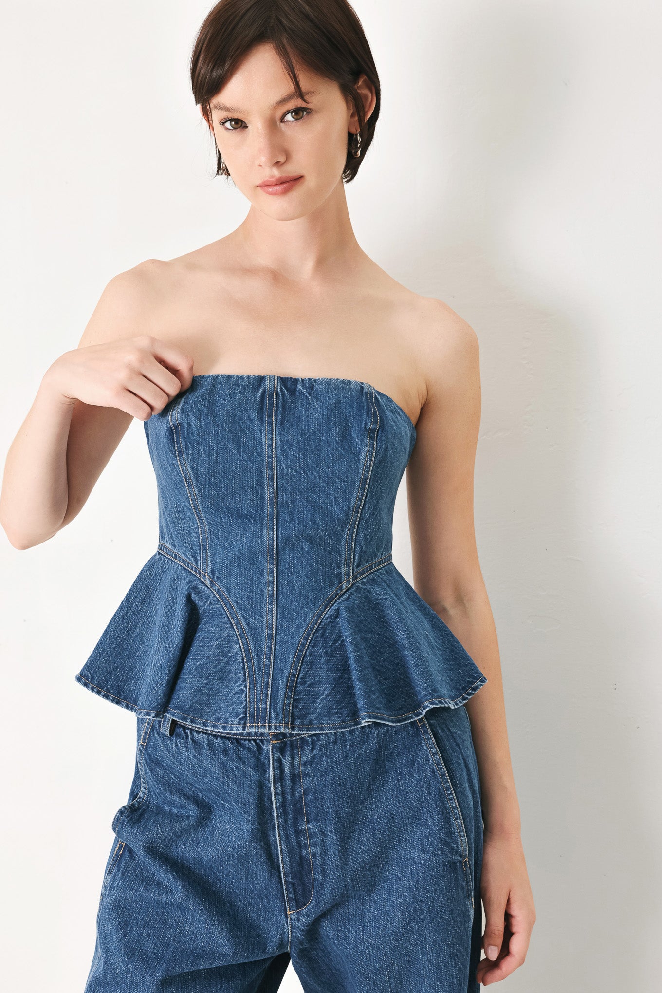 A washed denim top featuring strapless, ruffled peplum and back zipper closure