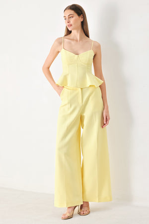 Woman wearing a yellow peplum cami top with back zipper closure | FREEMARKET | Flying Tomato