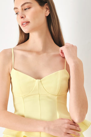 Woman wearing a yellow peplum cami top with back zipper closure | FREEMARKET | Flying Tomato