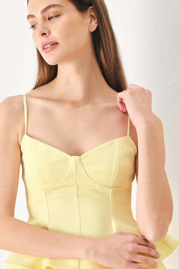 Woman wearing a yellow peplum cami top with back zipper closure | FREEMARKET | Flying Tomato