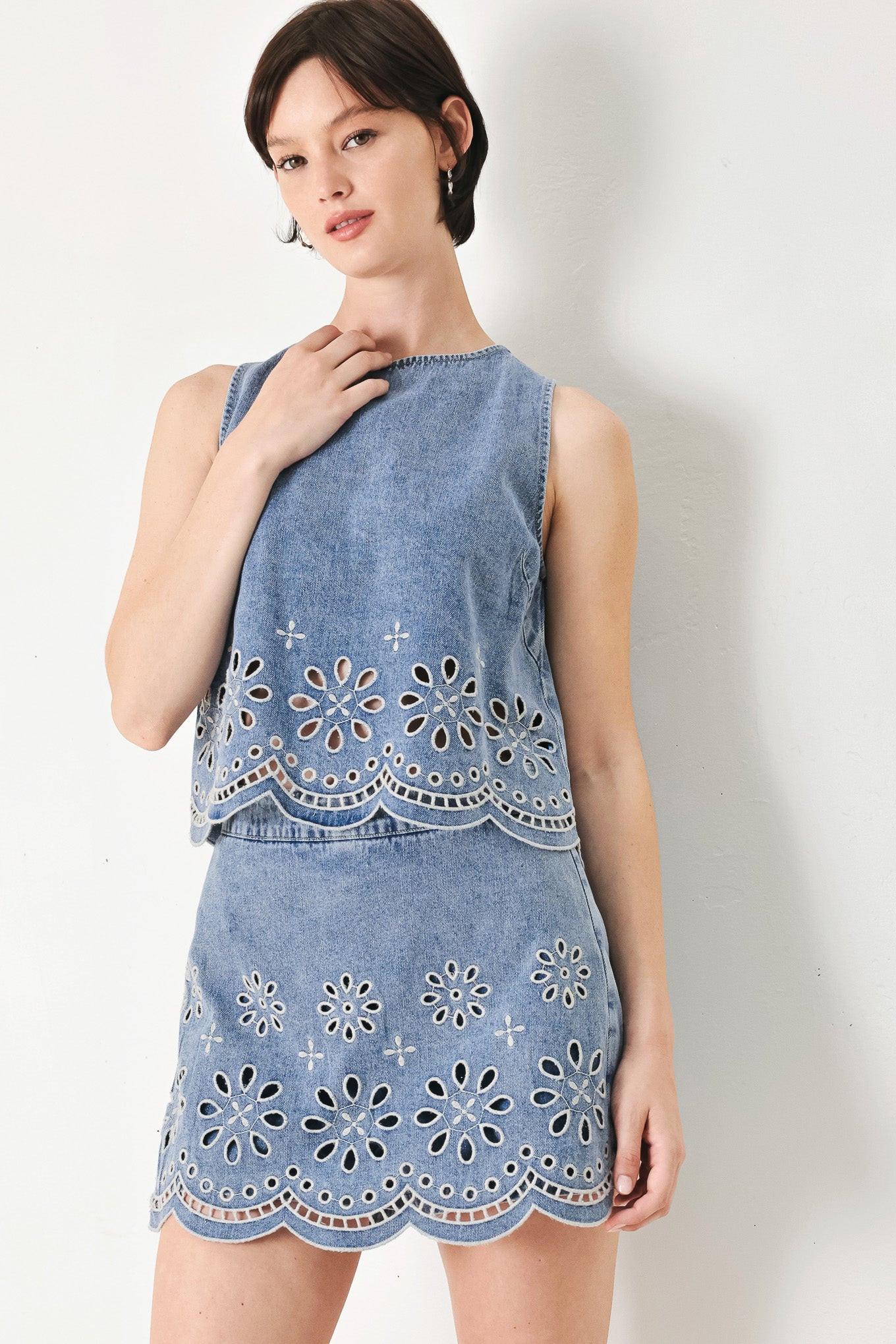 A washed denim top featuring round neckline, sleeveless, eyelet cut out and scallop hem with back tie closure