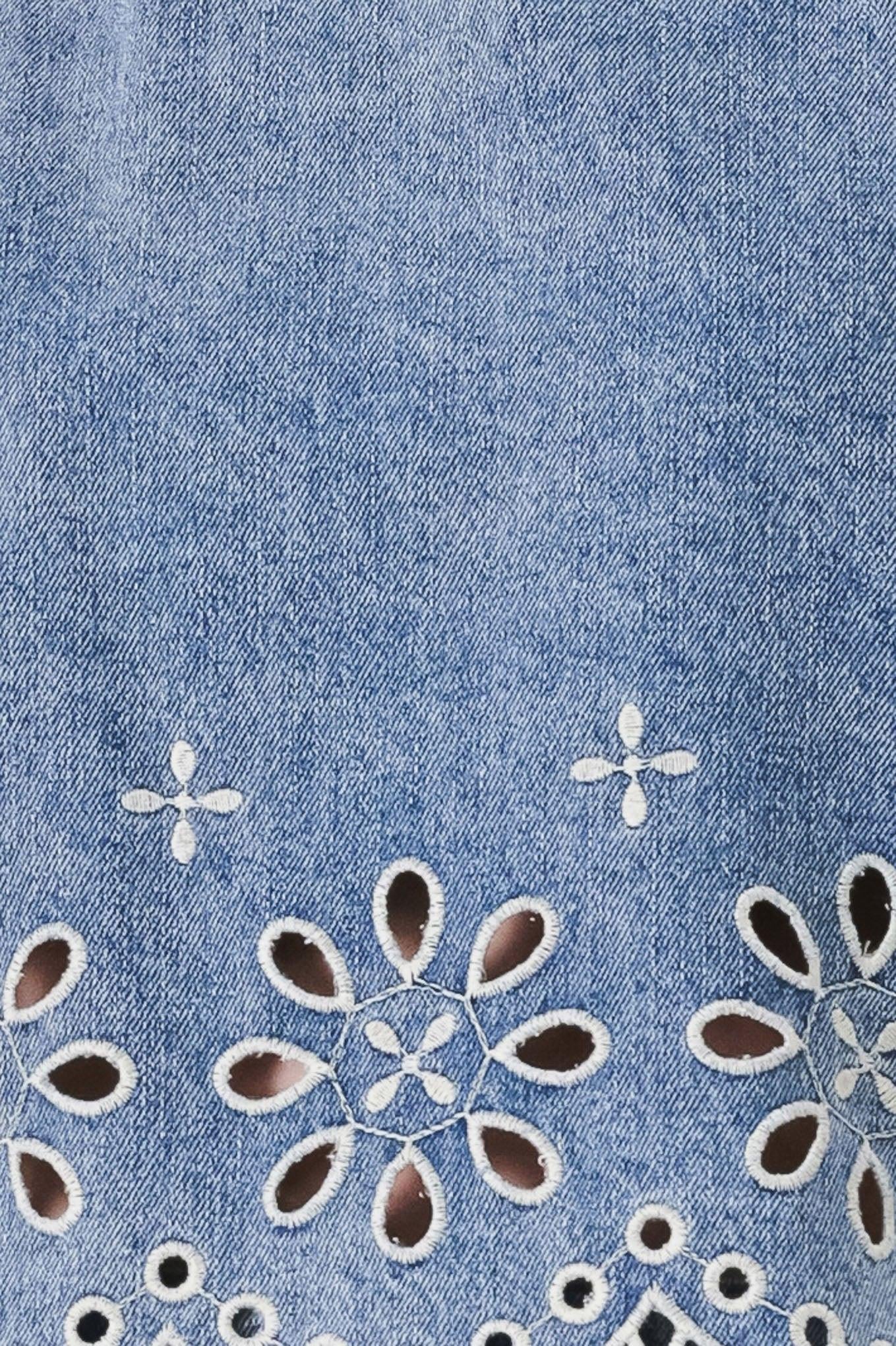 Close-up of a blue denim fabric with white floral embroidery