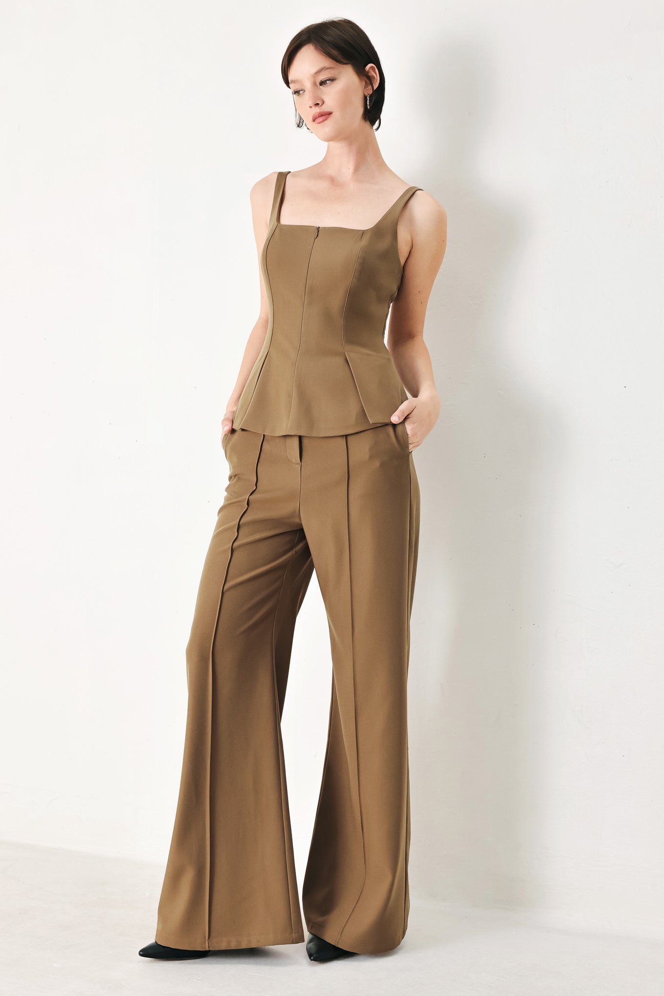 A solid woven top with square neckline, sleeveless, front zipper closure and peplum.