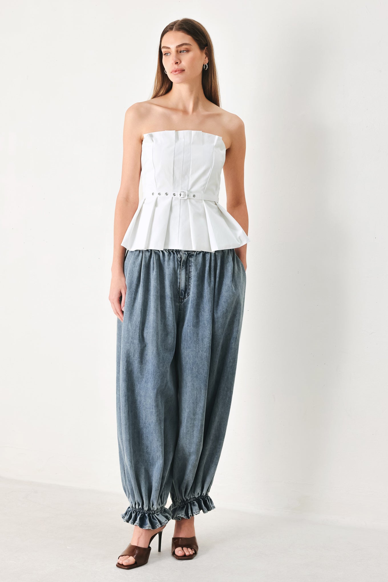 Woman wearing a white strapless top with a peplum waist and belt | Flying Tomato