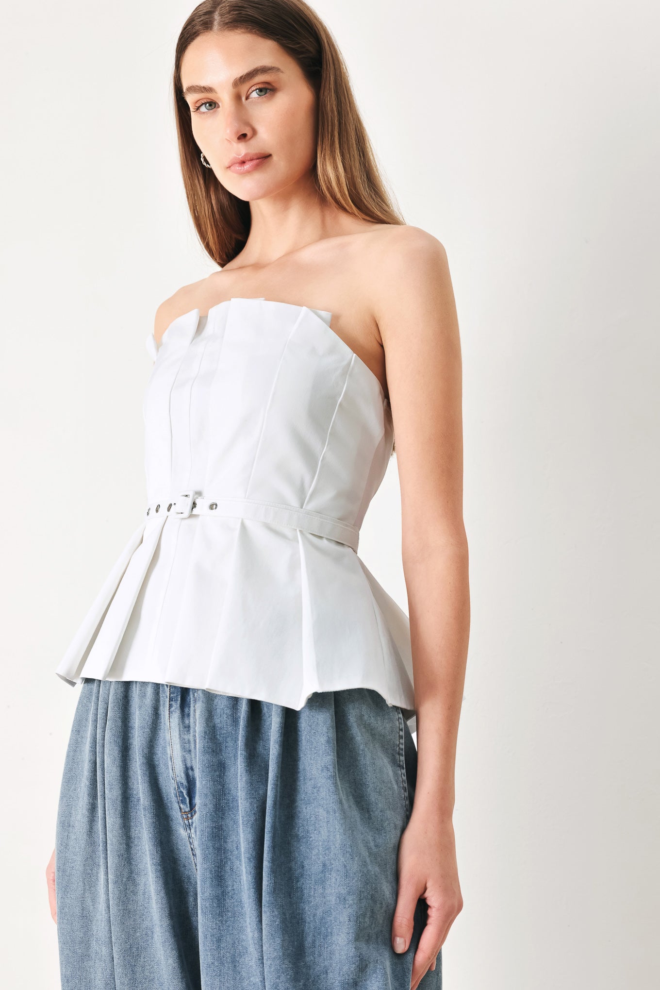 Woman wearing a white strapless top with a peplum waist and belt | Flying Tomato