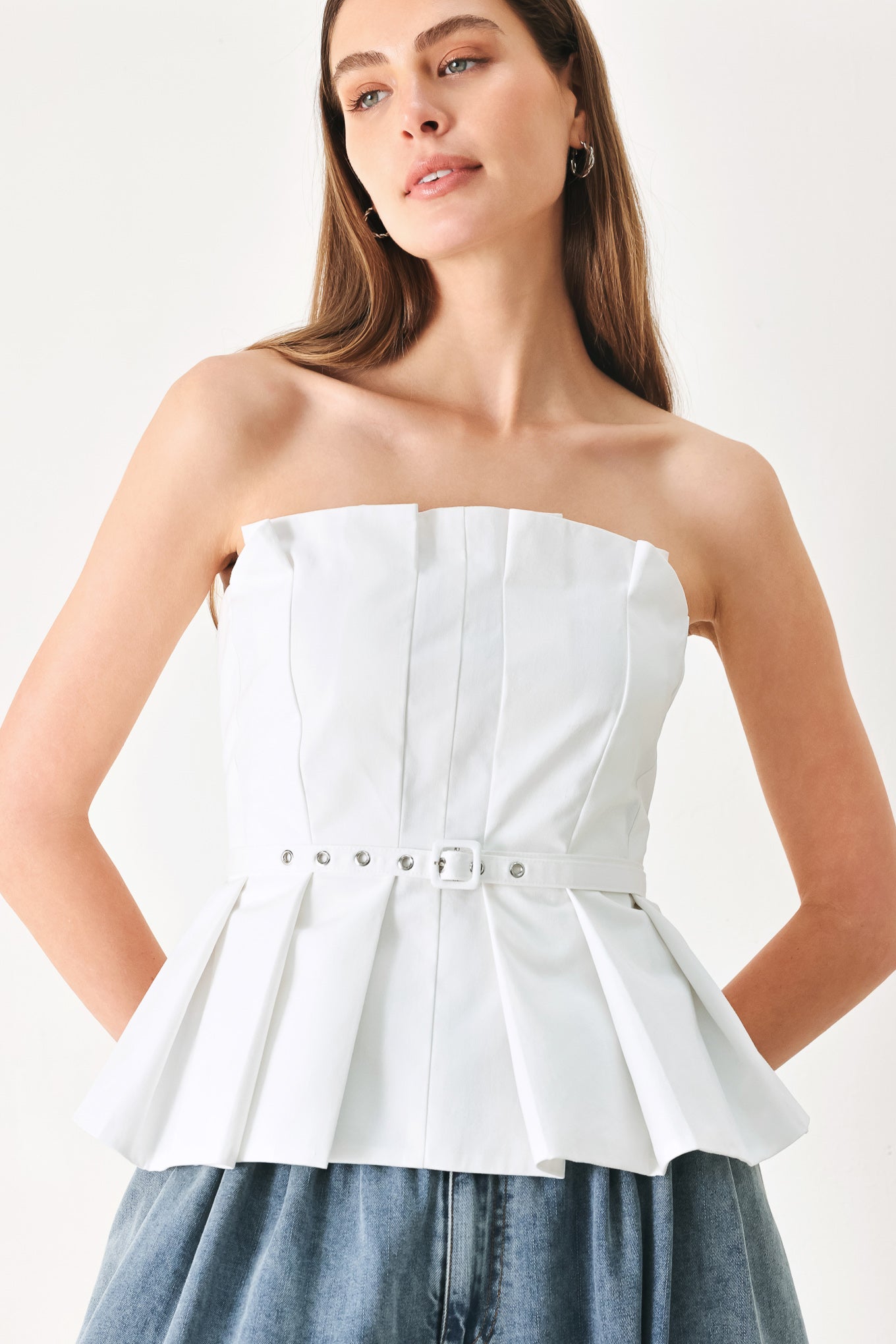 Woman wearing a white strapless top with a peplum waist and belt | Flying Tomato