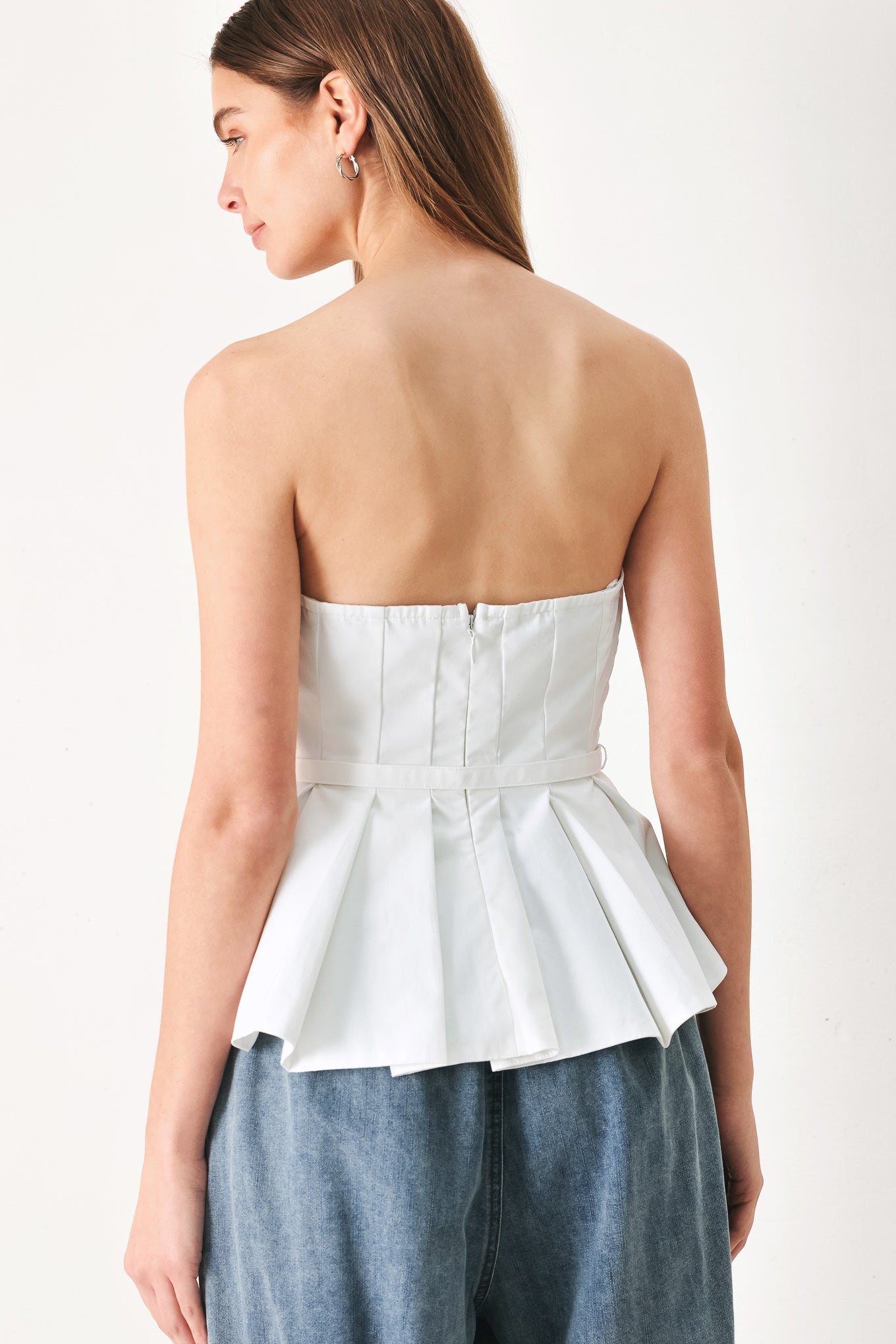 Woman wearing a white strapless top with a peplum waist and belt | Flying Tomato