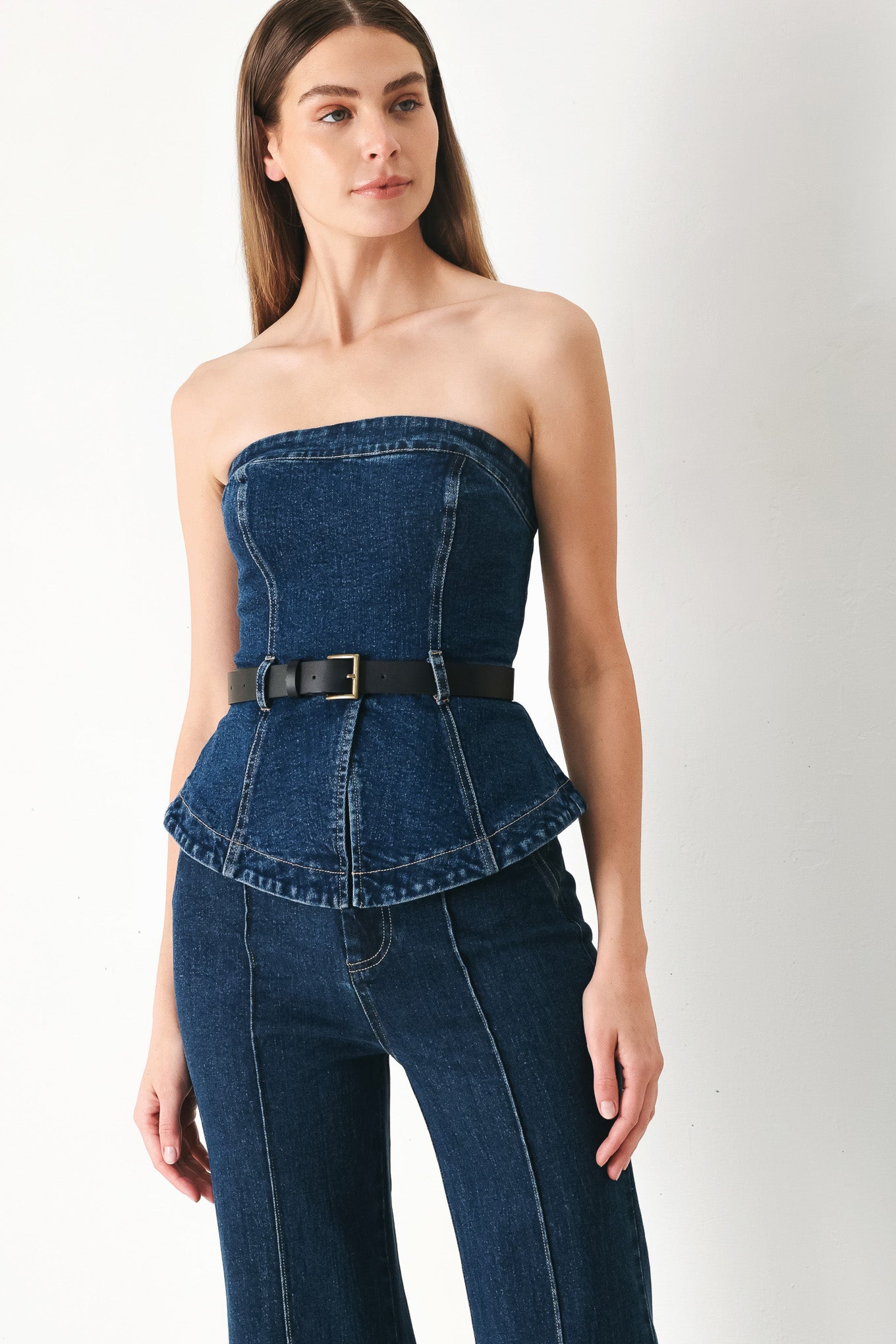 Woman wearing a strapless denim denim tube top featuring contrasting belt, front slit peplum and back zipper closure | FREEMARKET | Flying Tomato