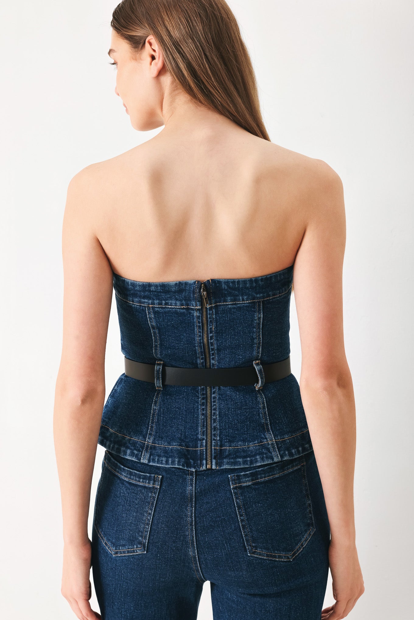 Woman wearing a strapless denim denim tube top featuring contrasting belt, front slit peplum and back zipper closure | FREEMARKET | Flying Tomato