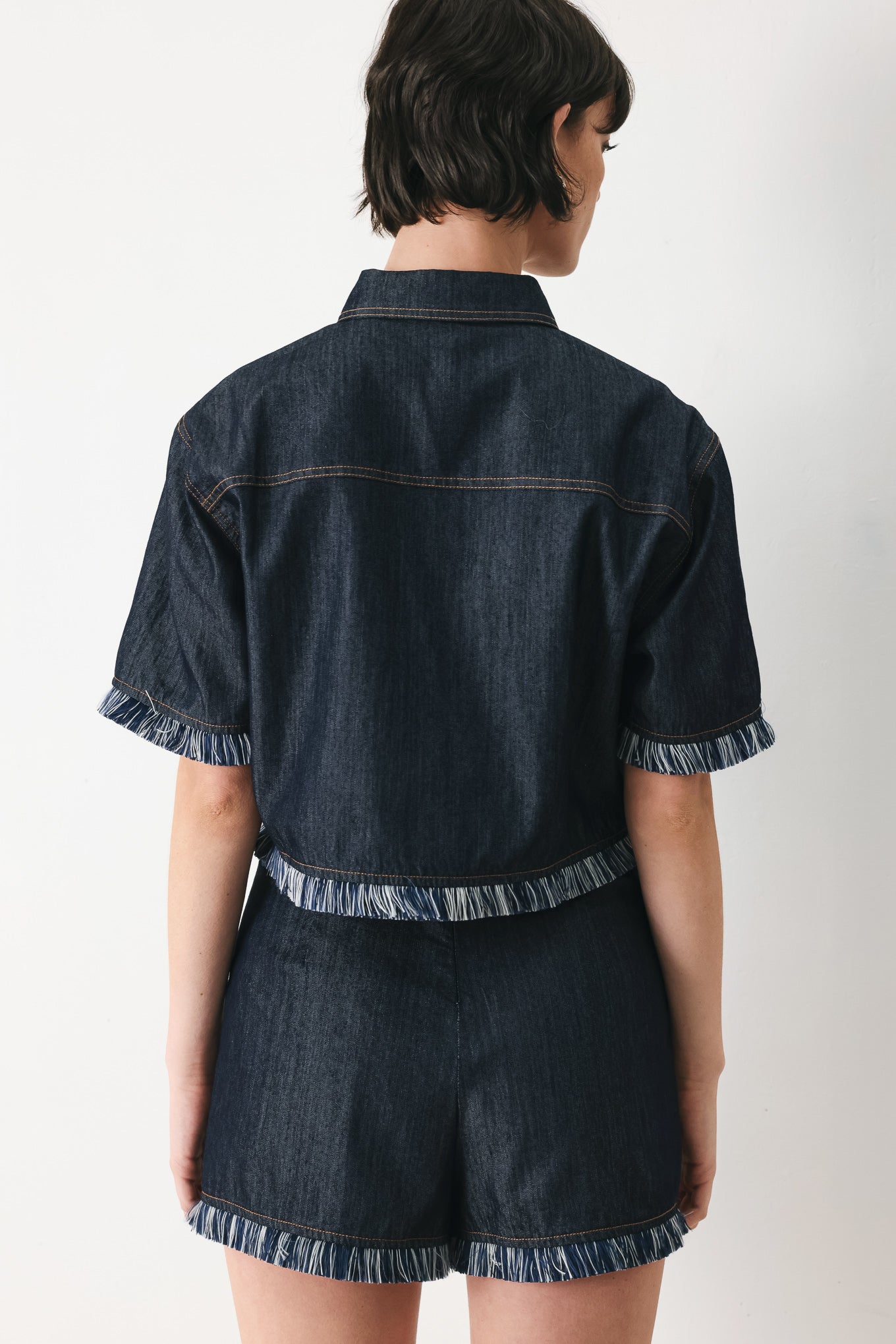 Woman wearing a dark denim crop jacket featuring short sleeve with fray edge and button down closure | FREEMARKET
