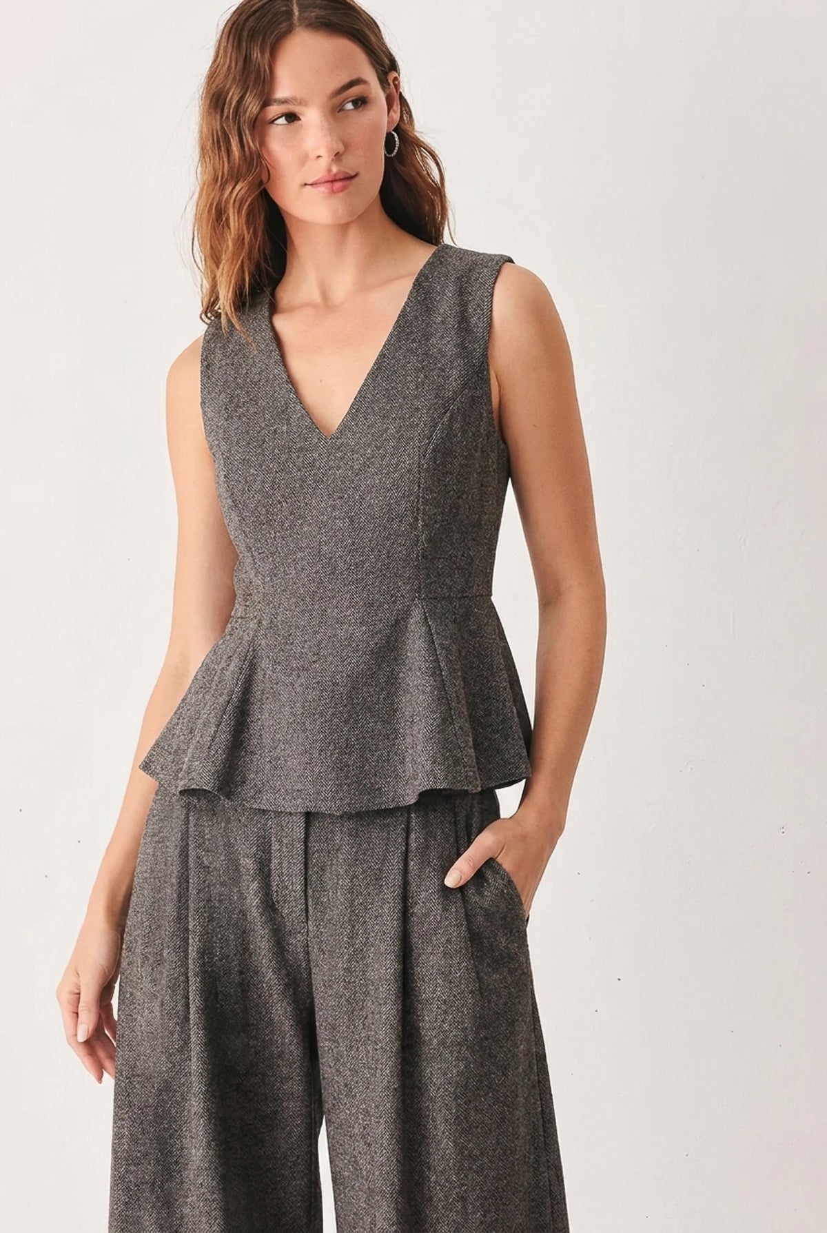 A solid woven top with V neckline, sleeveless, peplum and back zipper closure. Matching pant FP2191T