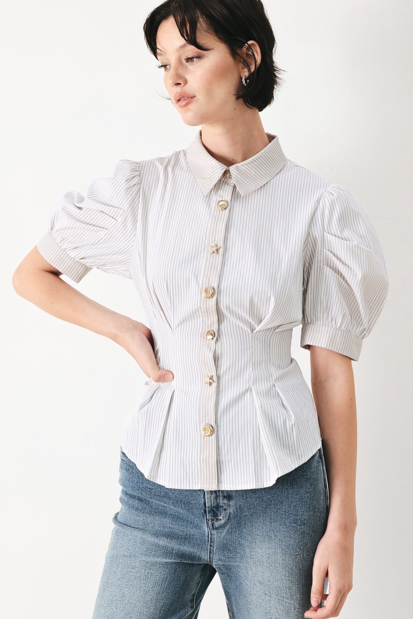 Woman wearing a taupe and white striped woven top featuring short puff sleeve, front button down, corset waist and peplum | FREEMARKET