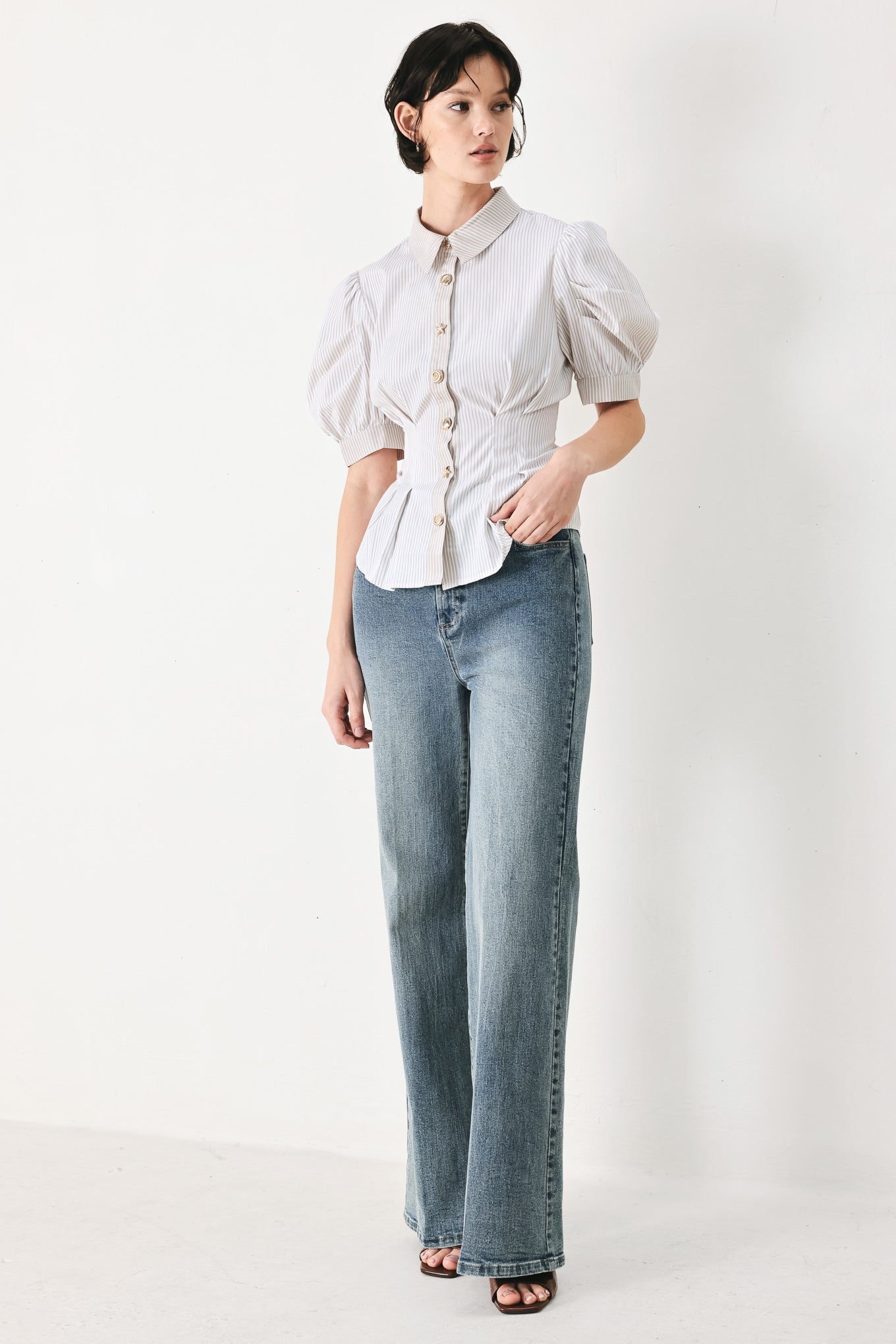 Woman wearing a taupe and white striped woven top featuring short puff sleeve, front button down, corset waist and peplum | FREEMARKET