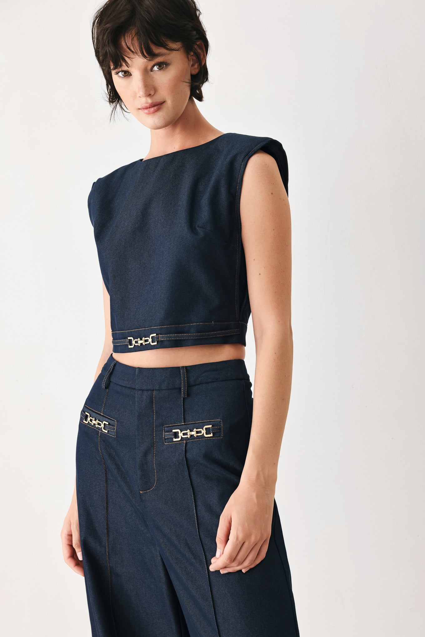 Woman wearing a navy blue sleeveless crop top with round neckline, hardware detail and back zipper closure | FREEMARKET