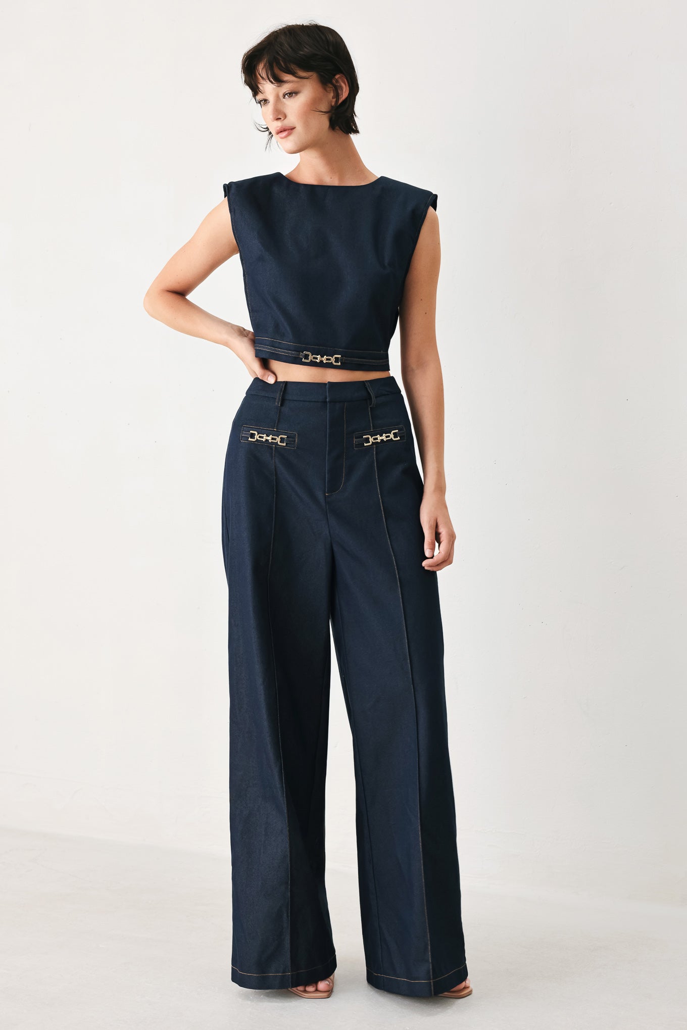 Woman wearing a navy blue sleeveless crop top with round neckline, hardware detail and back zipper closure | FREEMARKET