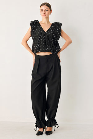 Woman wearing a black polka dot top featuring V neckline with bubble sleeve and waist | FREEMARKET